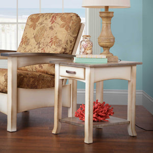 Coastal end table with weathered gray top and cream base holding a lamp and shells in a beach themed living room