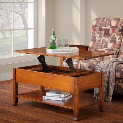 Lift top coffee table raised to laptop height holding a bottle and glasses beside a patterned chair by a window