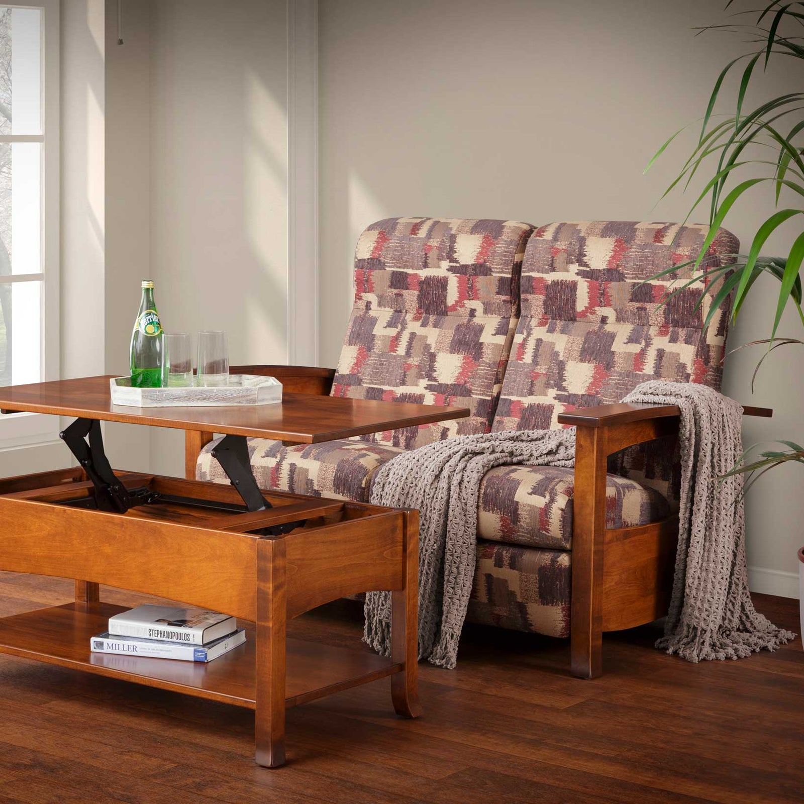 Reclining loveseat in geometric patterned fabric next to a raised lift top coffee table in a sunlit room