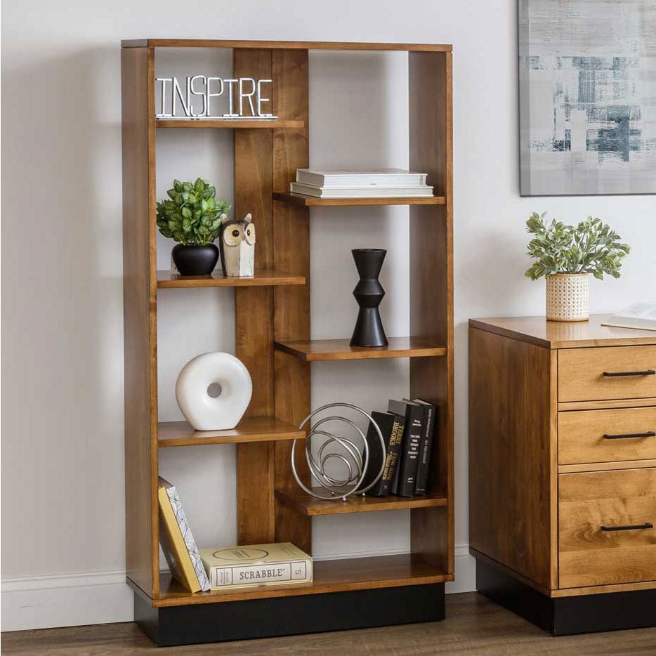 Modern staggered floating shelf bookcase in honey wood styled with books, plants and decor on a black plinth