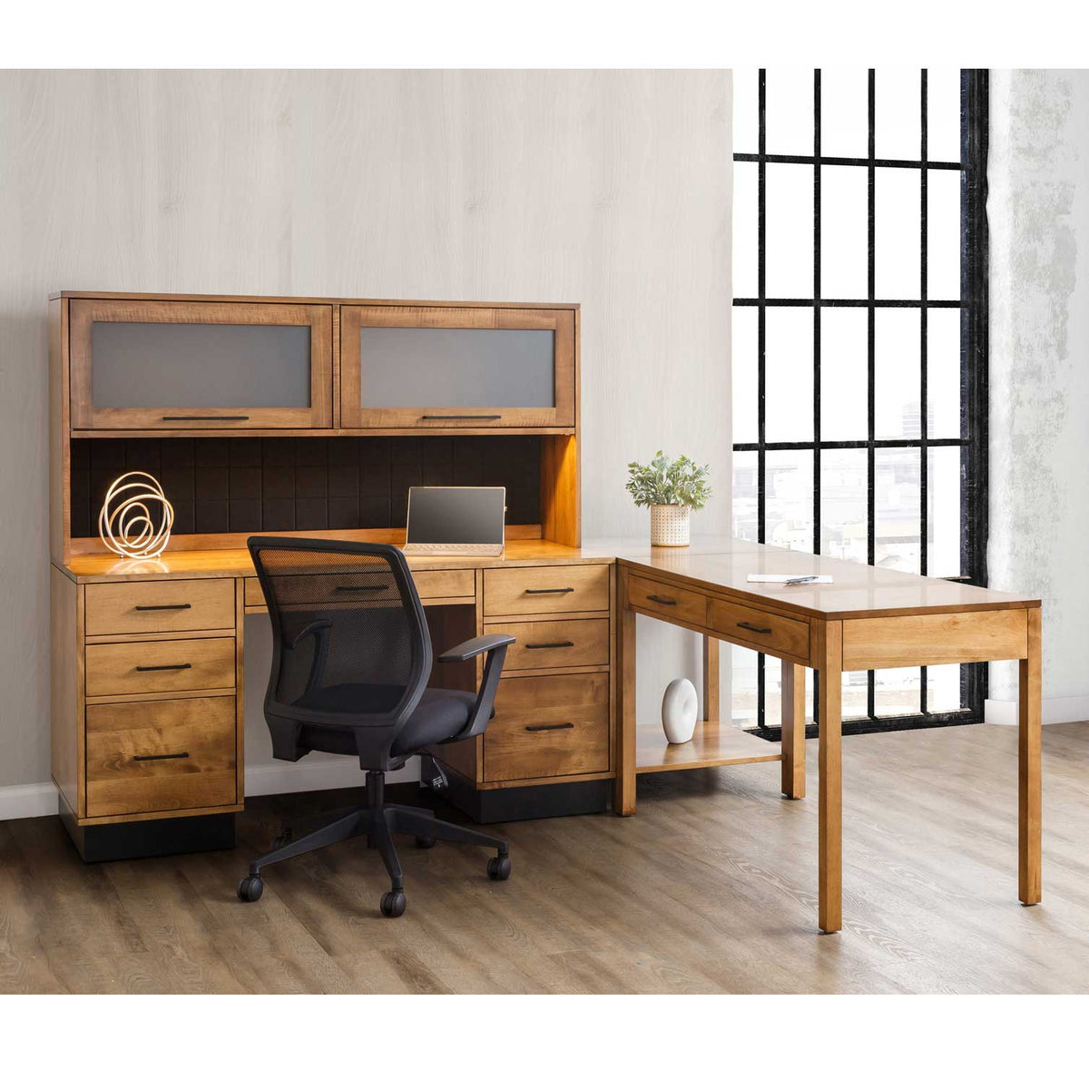 L-shaped modern office setup with a kneehole desk, lighted glass-door hutch, return table desk and mesh task chair