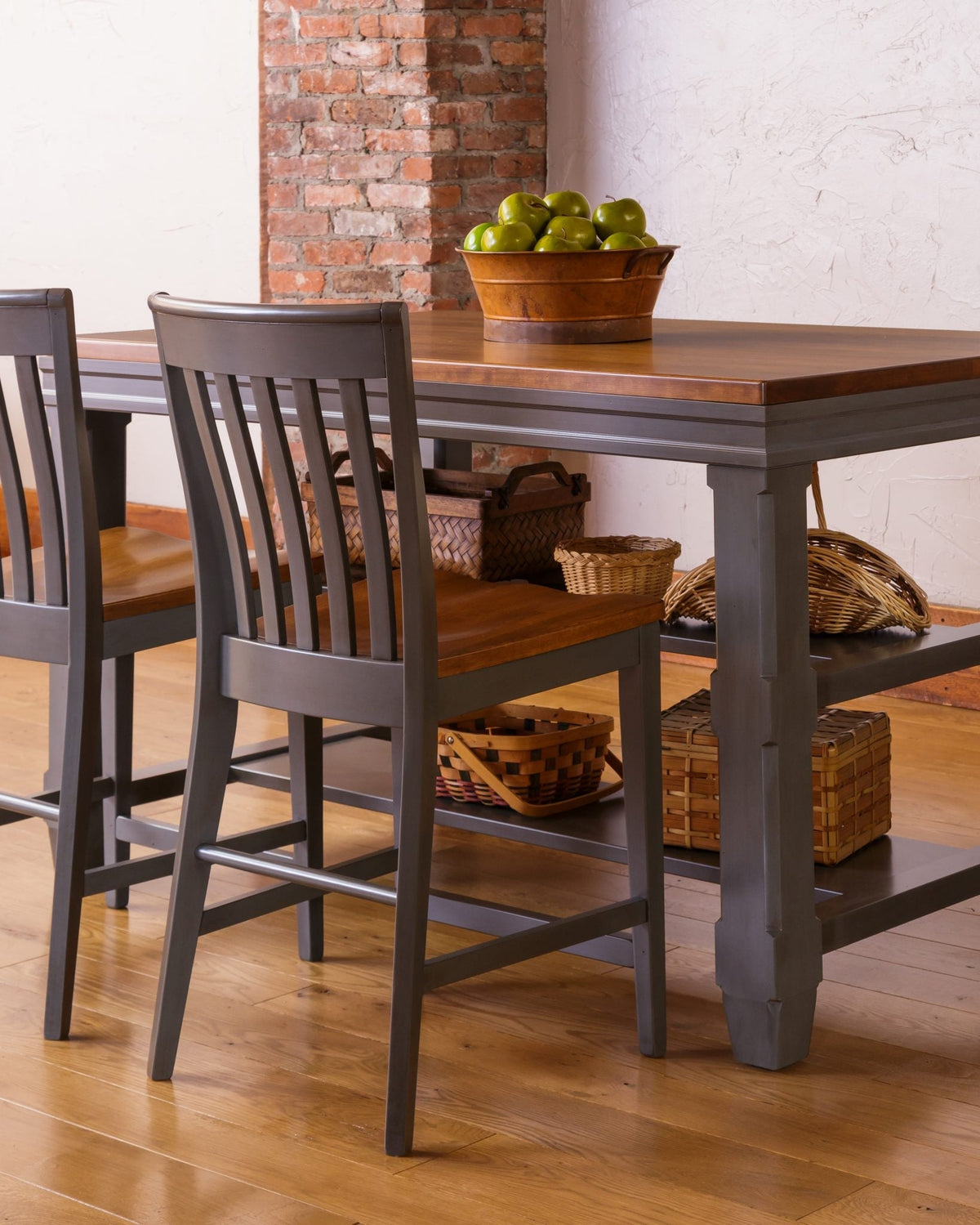 Two gray lumbar slat back counter stools tucked under a gray and brown counter height table on oak flooring