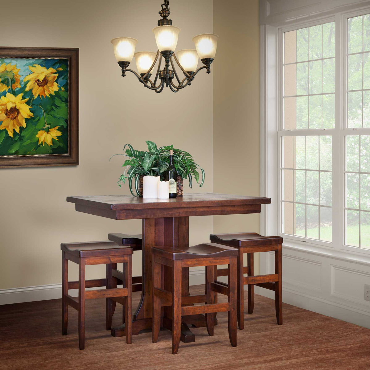Rustic cherry counter height gathering table with four saddle seat stools under a bronze chandelier