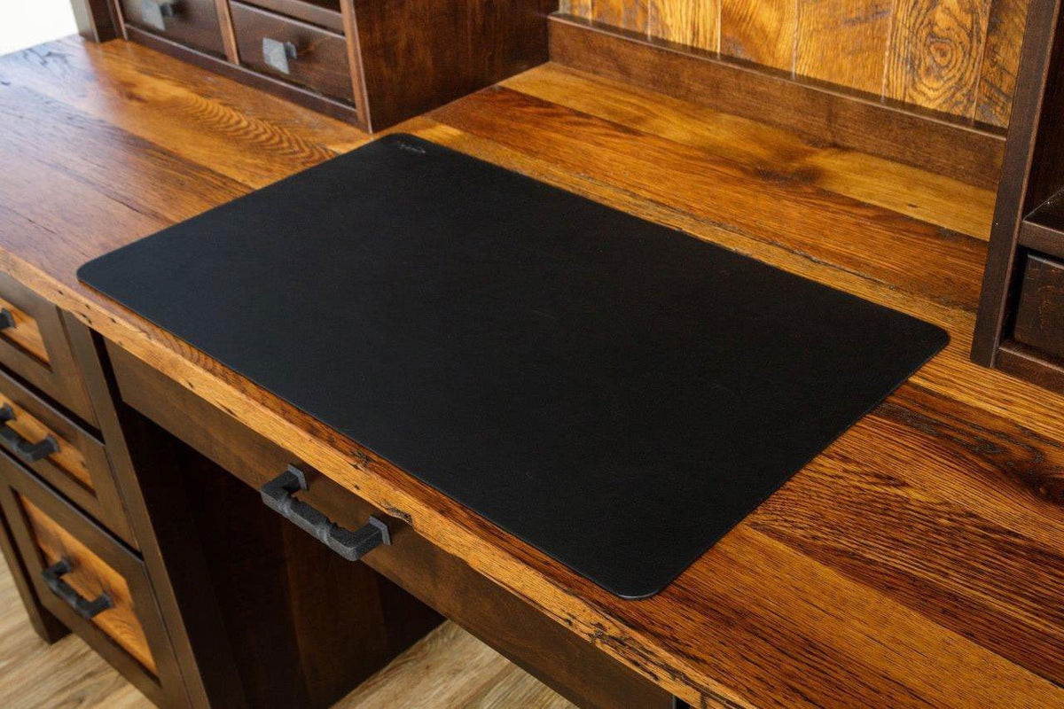 Black desk pad centered on the reclaimed oak work surface, with the hutch drawers and forged pulls around it