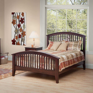 Espresso arched spindle bed with a curved slat headboard and footboard, styled with a tan patchwork quilt