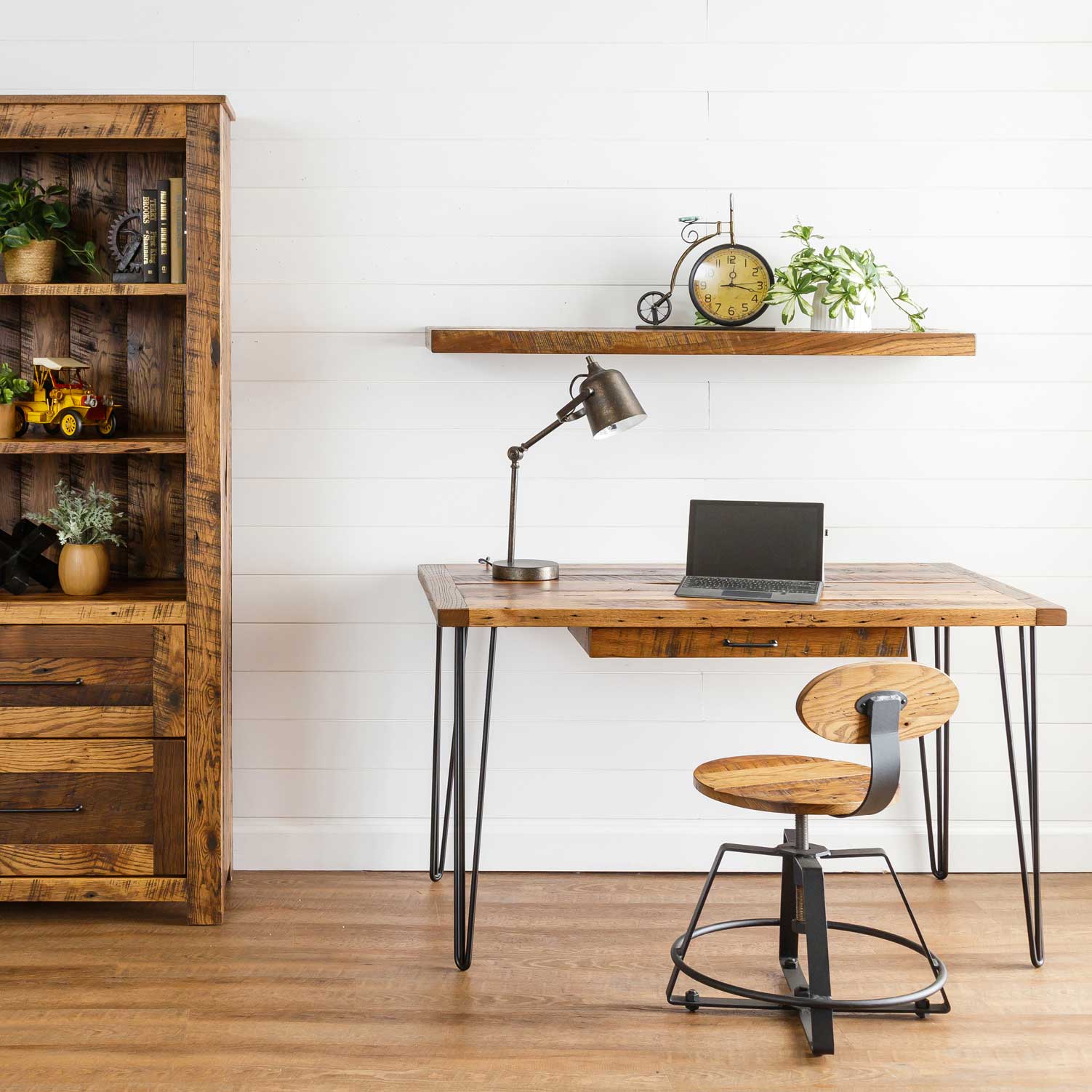Reclaimed wood writing desk with black hairpin legs and a laptop, styled with a task lamp, spinning stool and barnwood bookcase