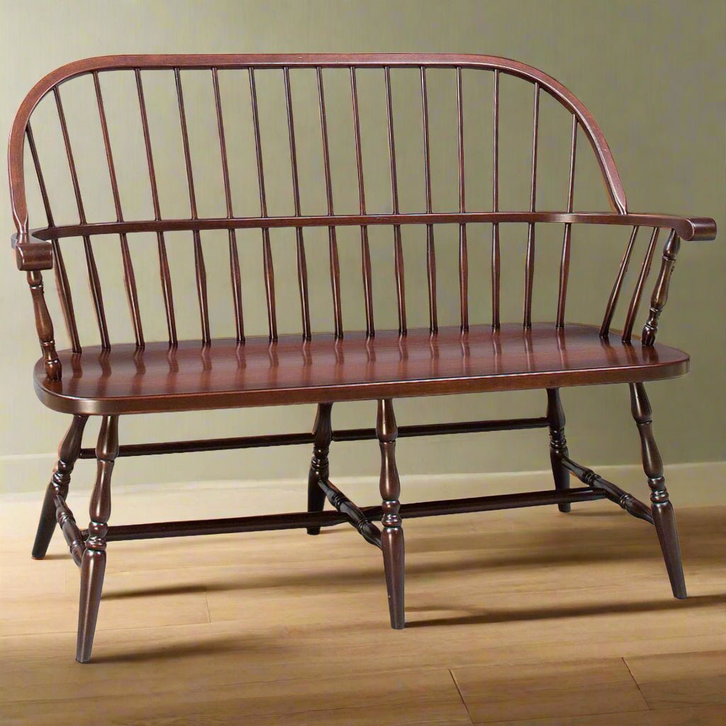 Cherry continuous arm Windsor bench with a bowed spindle back, oval plank seat and turned stretcher base