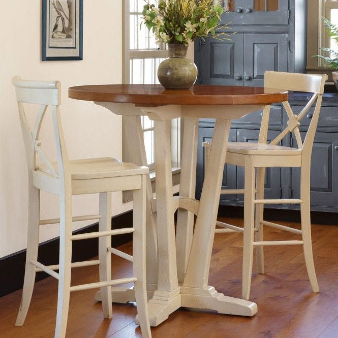 Round pub height table with a cherry top and white trestle pedestal flanked by two X back bar stools