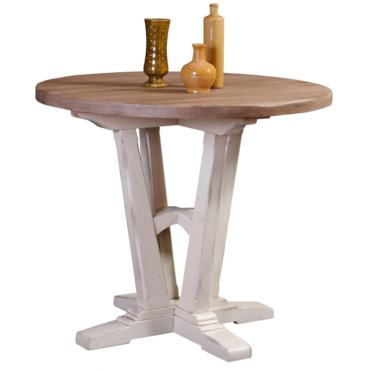 Round dining table with a weathered natural top and distressed white pedestal base styled with pottery vases