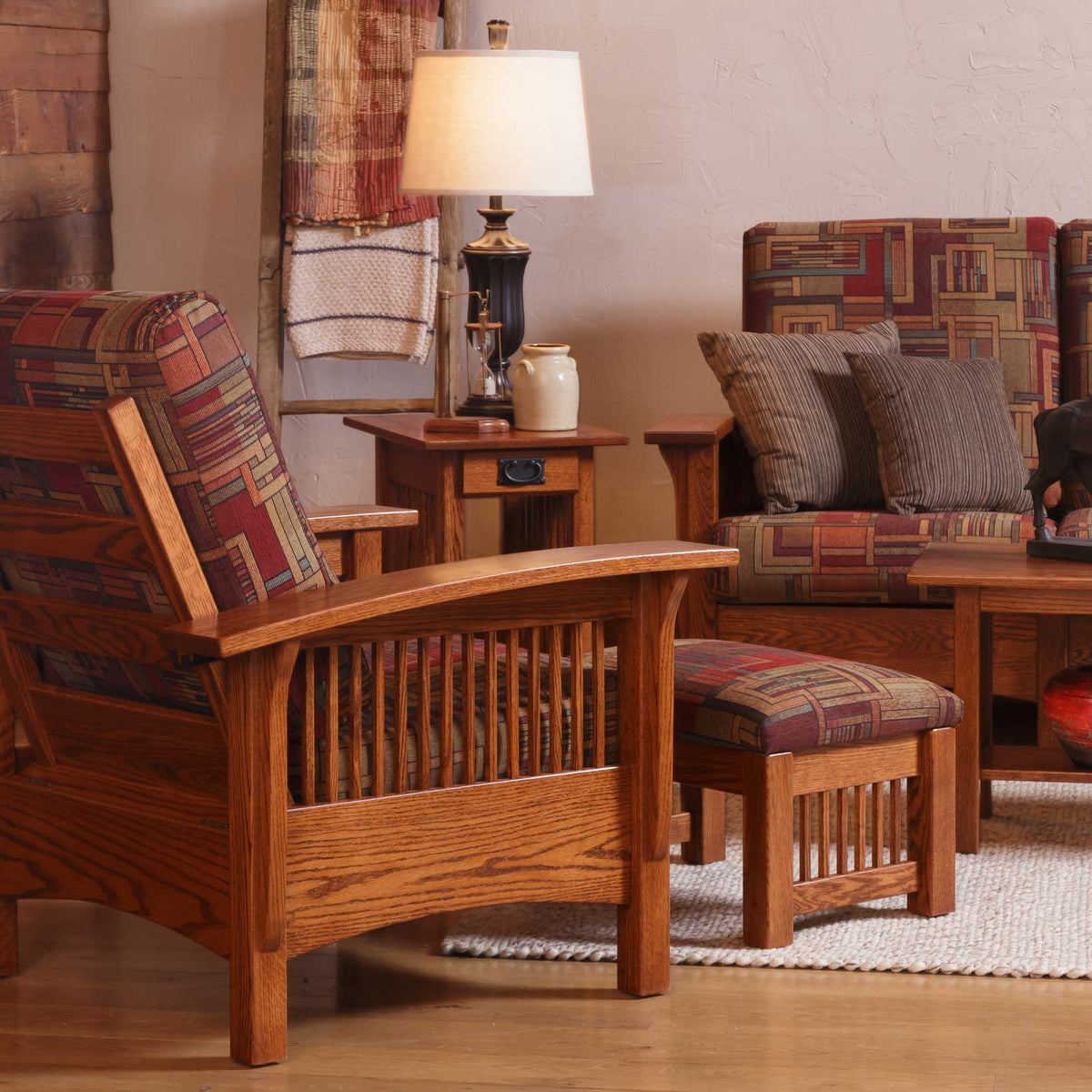 Oak Morris chair and ottoman in geometric fabric beside a slatted end table and lamp in a rustic room
