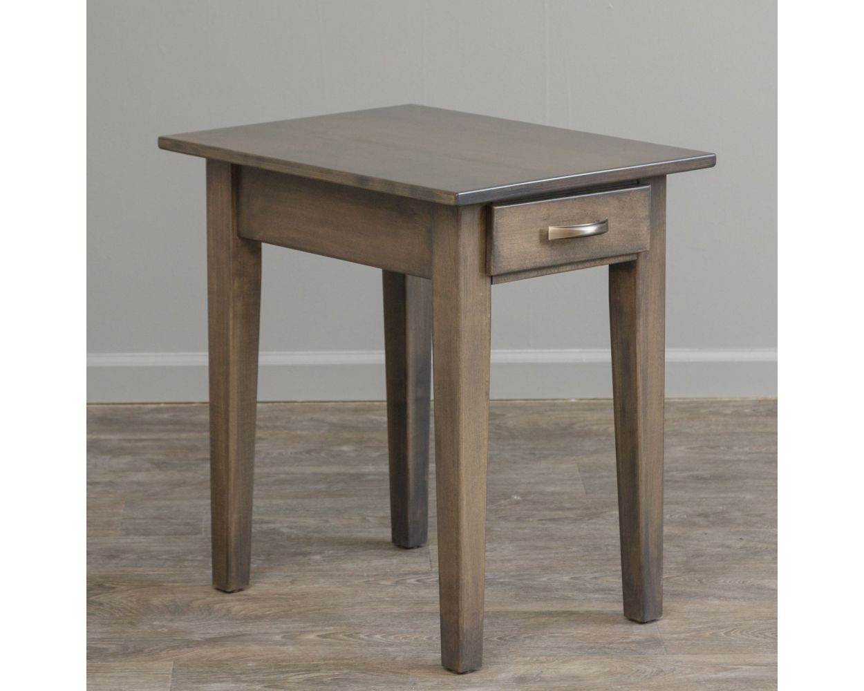 Gray stained shaker end table with one drawer and tapered legs between two upholstered chairs by a window