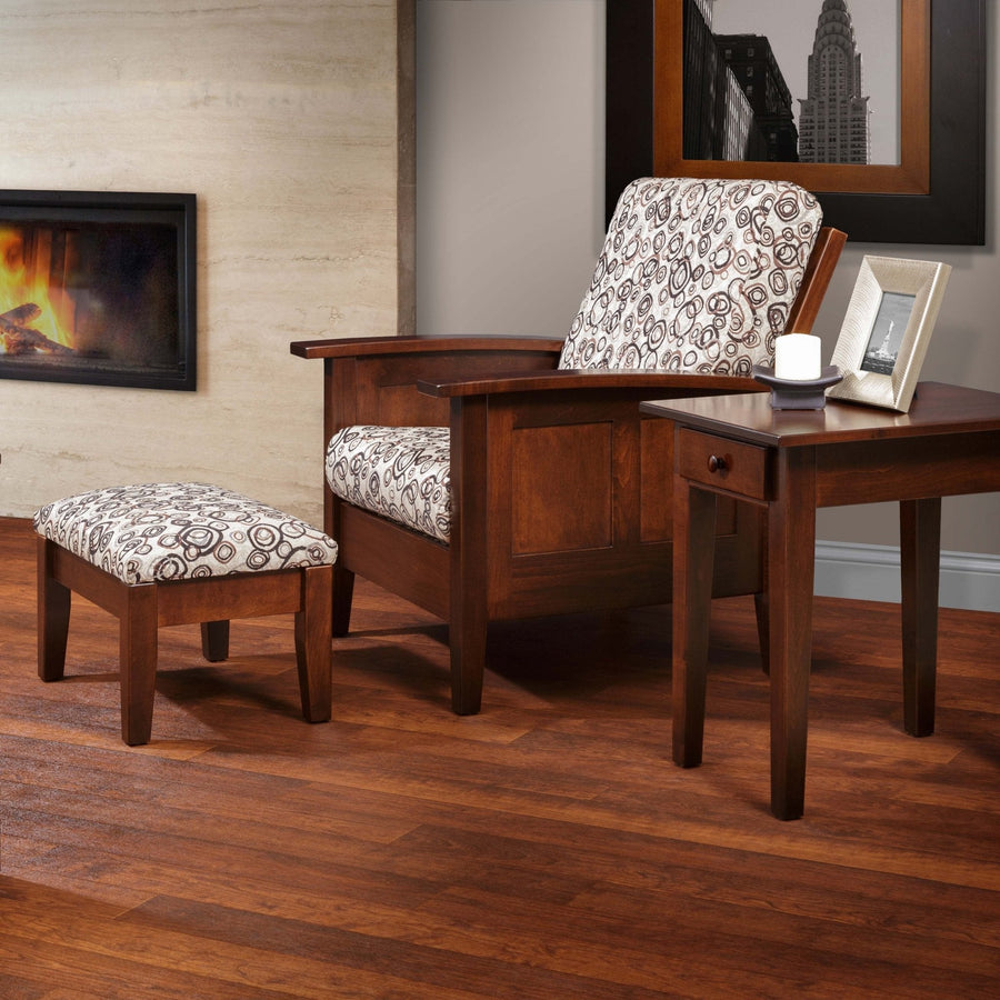 Cherry Shaker Morris chair with matching upholstered ottoman staged on hardwood flooring beside an end table and fireplace