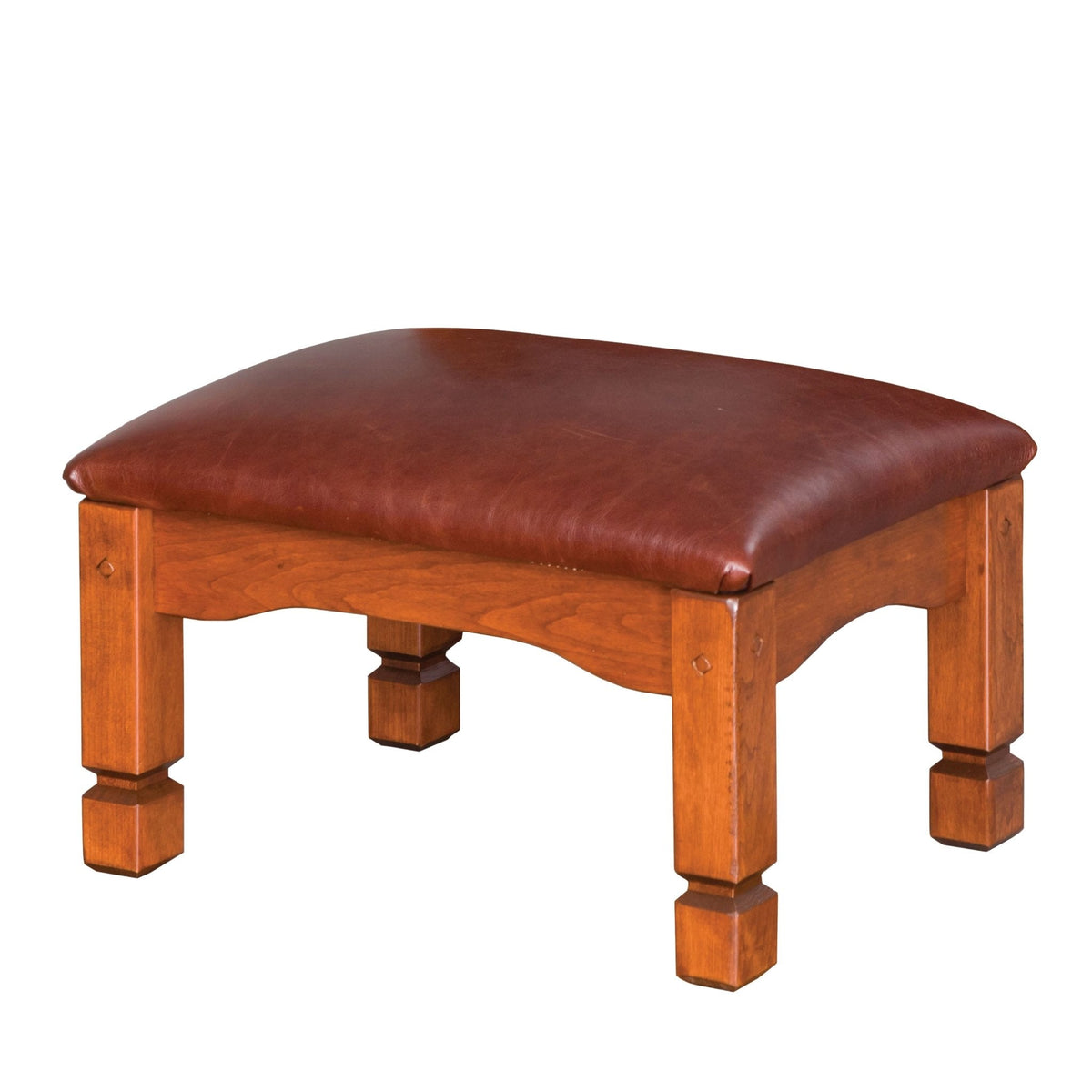 Wood frame ottoman in medium cherry with a burgundy leather seat, scalloped apron and stepped square feet