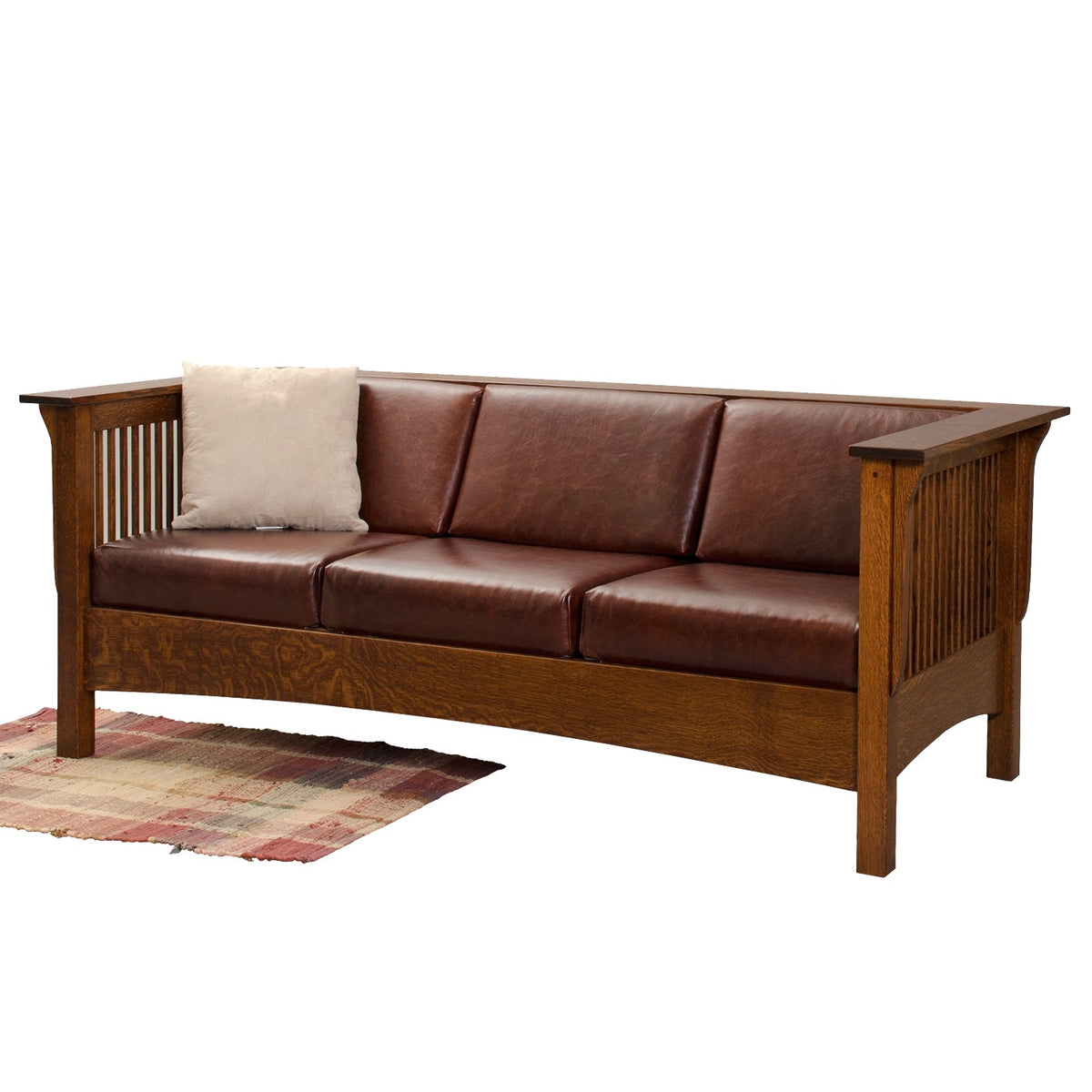 Mission slat side sofa in quartersawn oak with burgundy leather cushions, cream pillow and a plaid rug alongside
