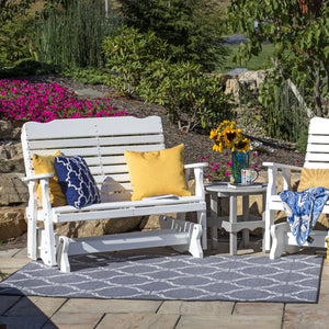 White poly glider bench with yellow and navy pillows beside a matching glider chair and side table