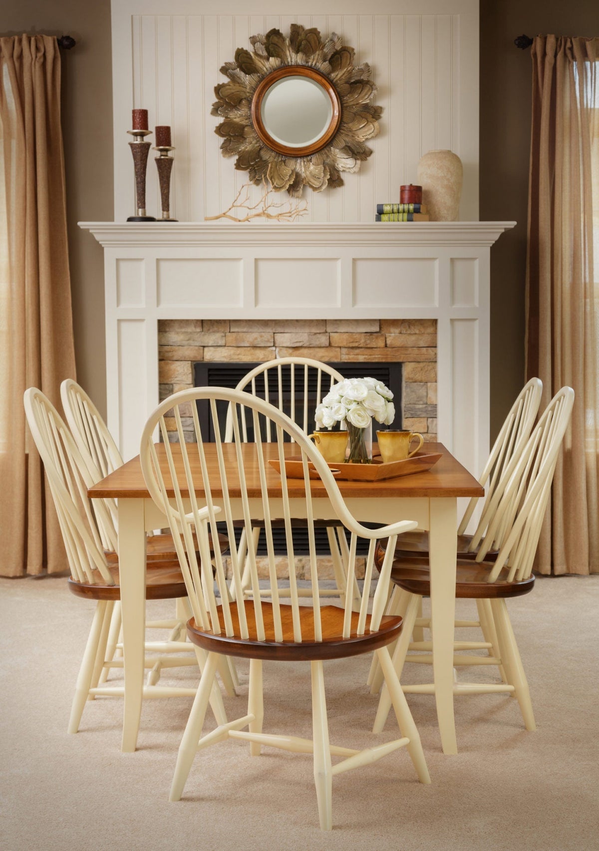 Cream painted Windsor dining set with bow back chairs, cherry seats and a two tone table by a stone fireplace