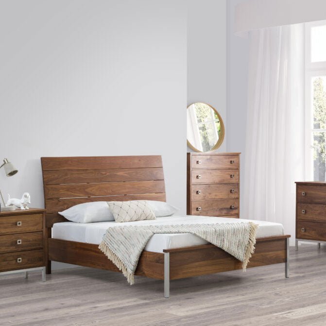 Mid century walnut bed with a plank headboard flanked by a nightstand and chest in a light gray bedroom