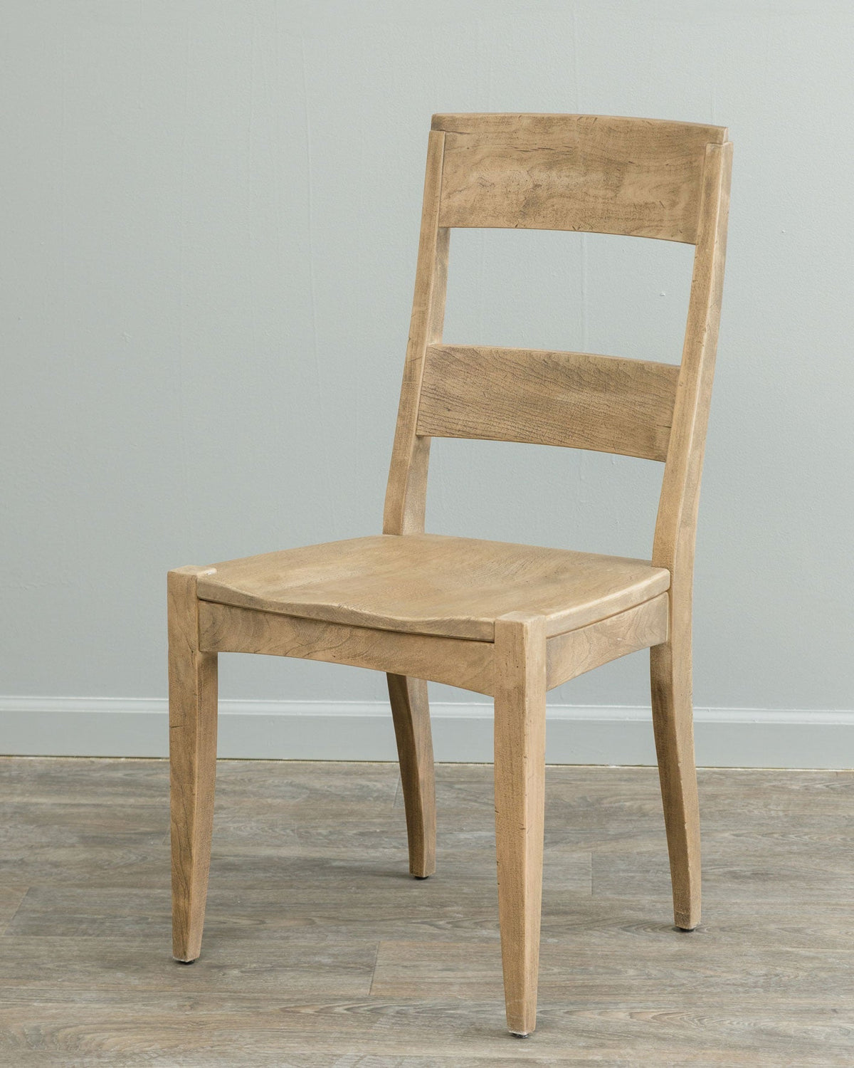 Weathered natural dining chair with a wide two slat back and saddle seat photographed against a gray wall
