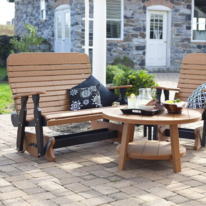 Cedar and black poly 4 foot easy glider bench with curved slat back beside a round poly coffee table on pavers