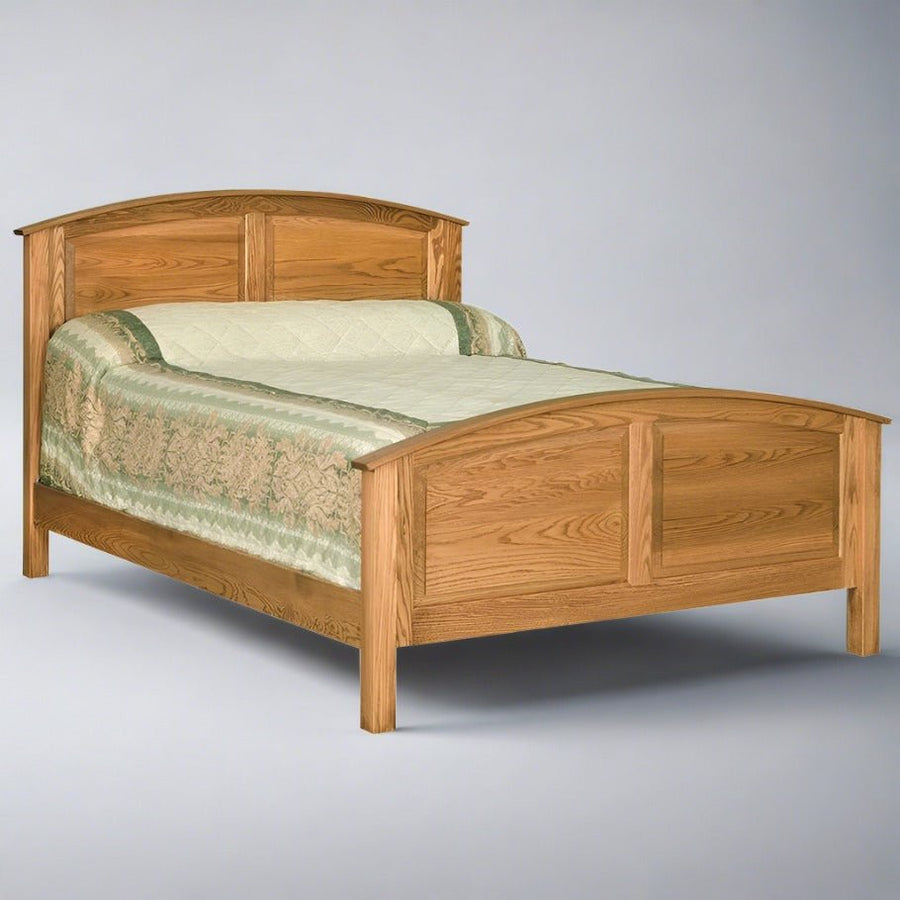 Curved raised panel oak bed with arched headboard and footboard panels and a sage floral coverlet
