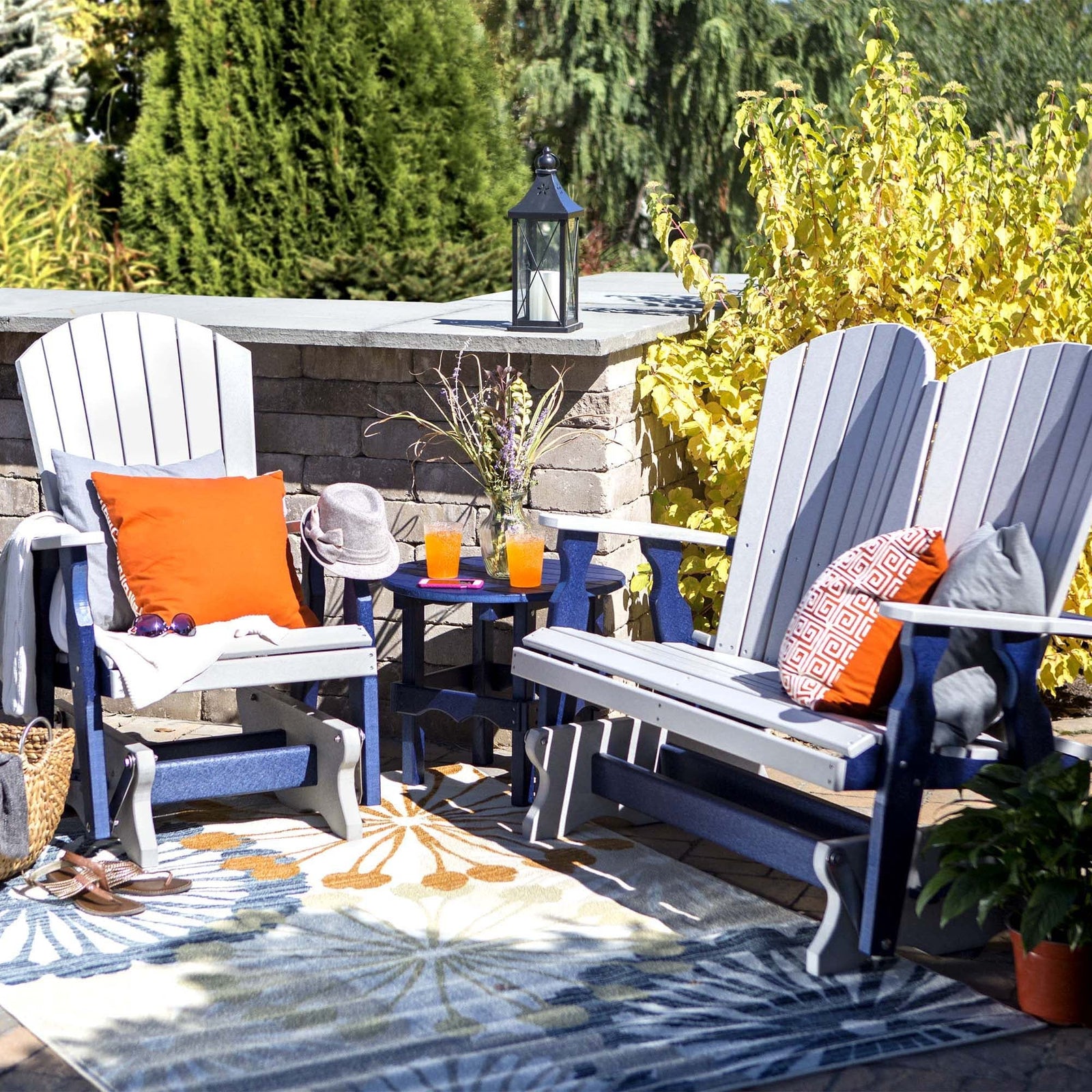 Gray and navy poly fanback glider chair, glider loveseat and round side table on a floral outdoor rug