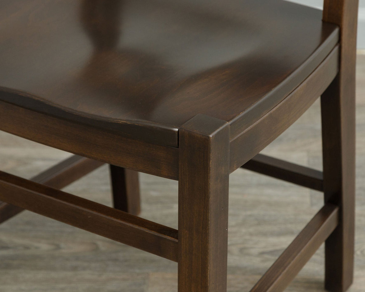 Close up of a dark stained chair seat corner showing the saddle scoop, square leg and side stretchers
