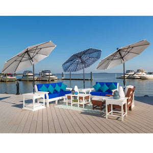Three market umbrellas in gray and blue check shading white poly sofas with blue cushions on a marina dock