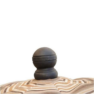 Black turned wood finial cap topping the striped canopy of a patio umbrella on a white background