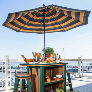Navy, tan and orange striped 9 foot umbrella over a green poly kitchen island bar table with swivel stools