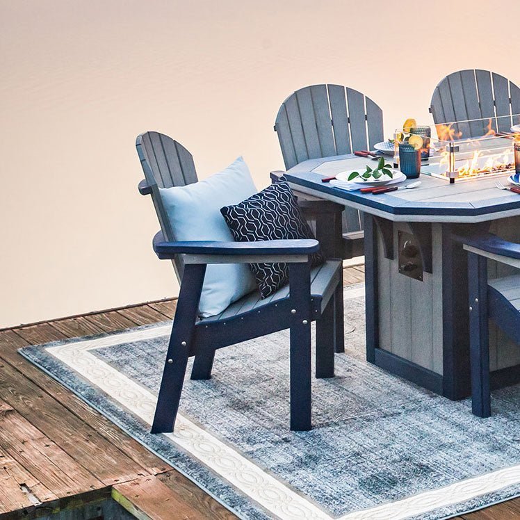 Navy and gray poly Adirondack dining chairs around a fire pit dining table on a dock at dusk