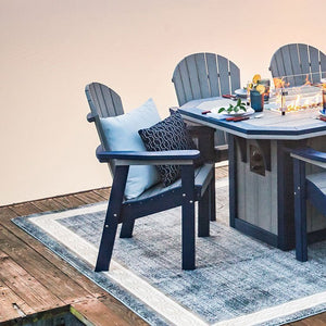 Navy and gray poly Adirondack dining chairs around a fire pit dining table on a dock at dusk