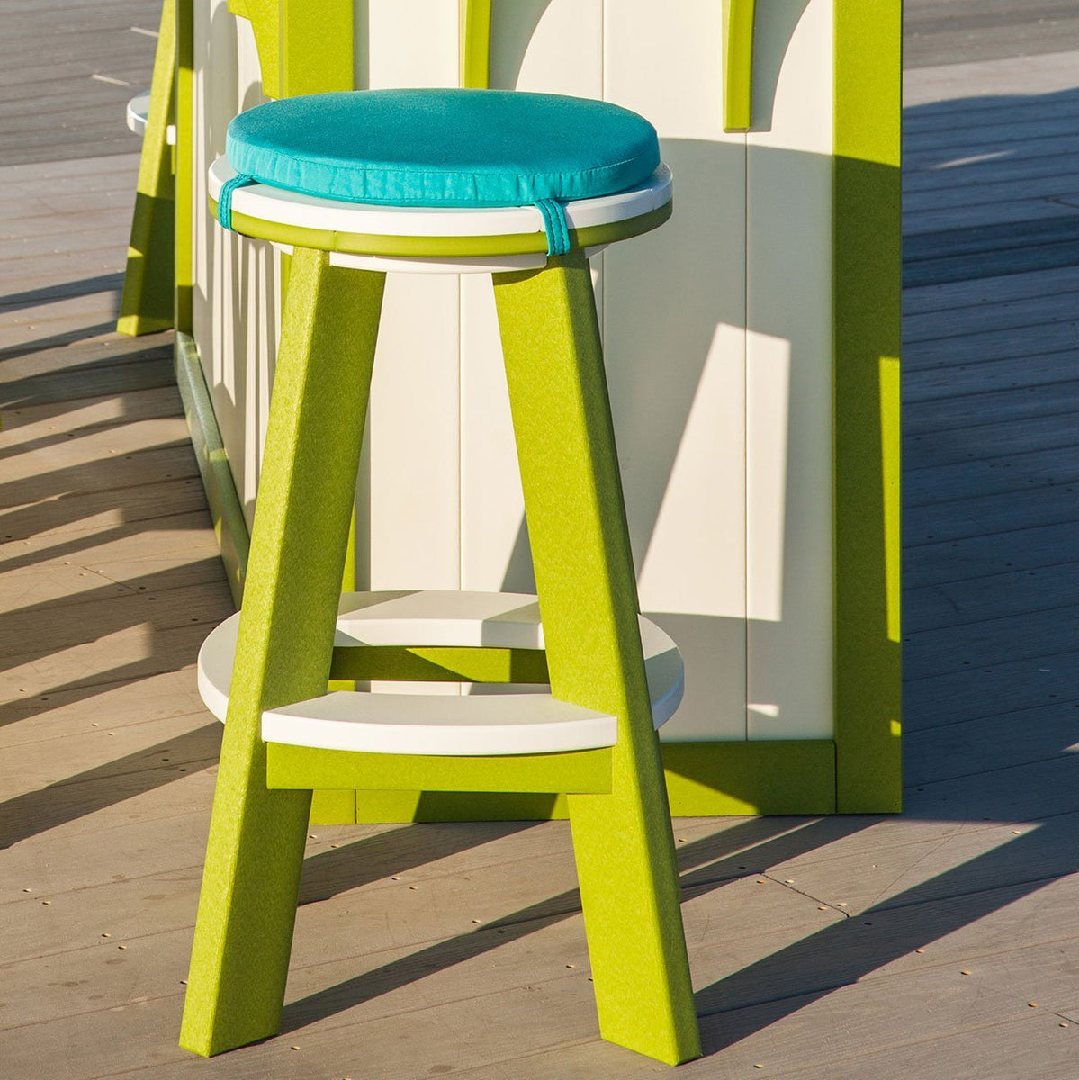 Lime green and white poly backless bar stool topped with a round turquoise cushion on a deck