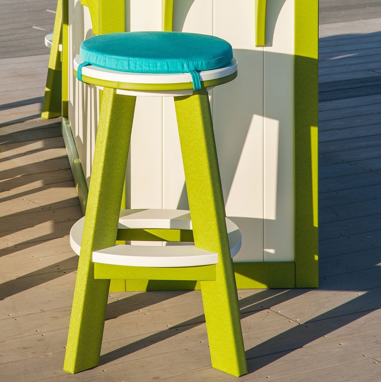 Gray two-tone poly backless round bar stool with light seat and footrest beside an outdoor bar