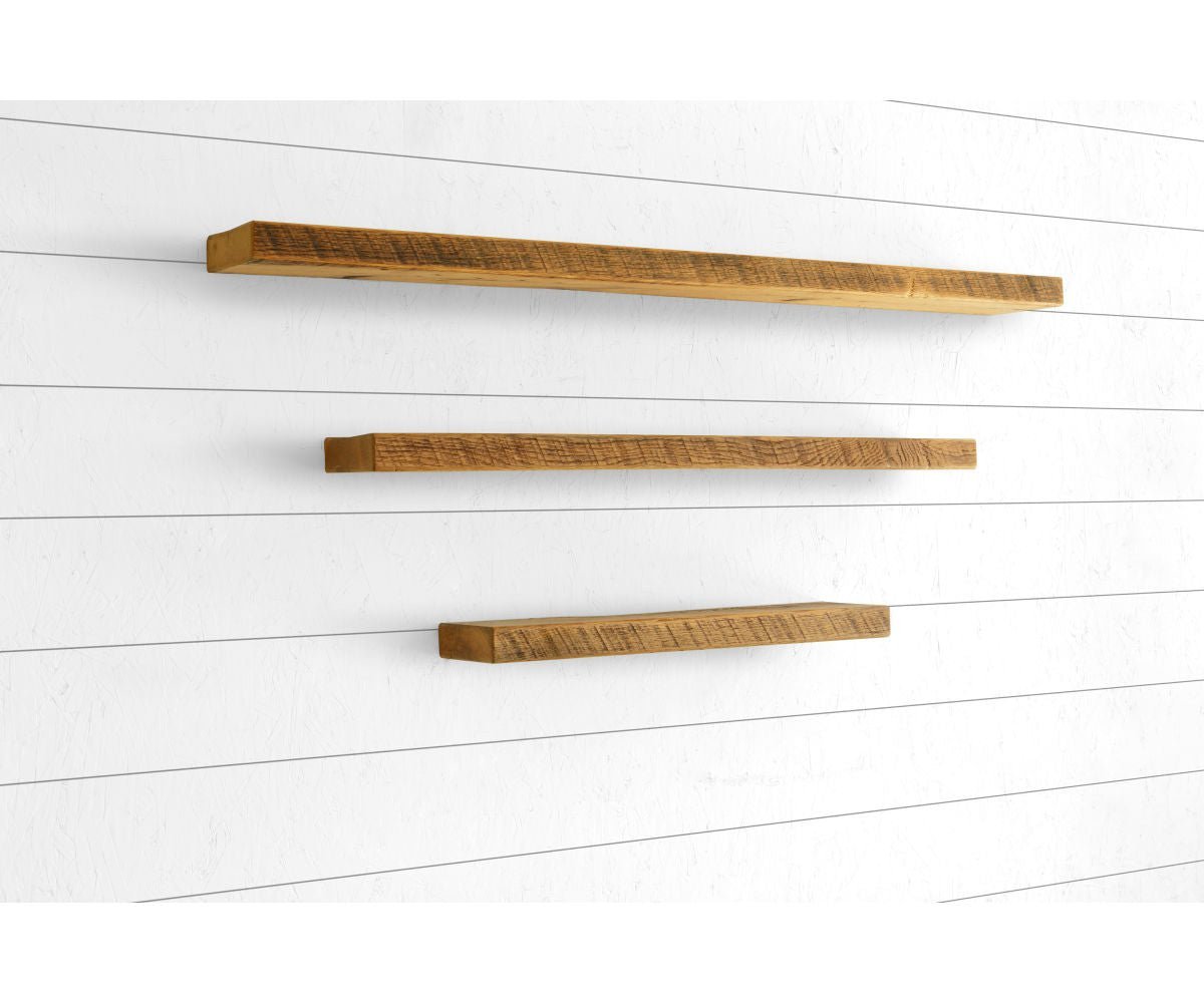 Three reclaimed wood floating shelves in a honey finish mounted at staggered heights on a white shiplap wall