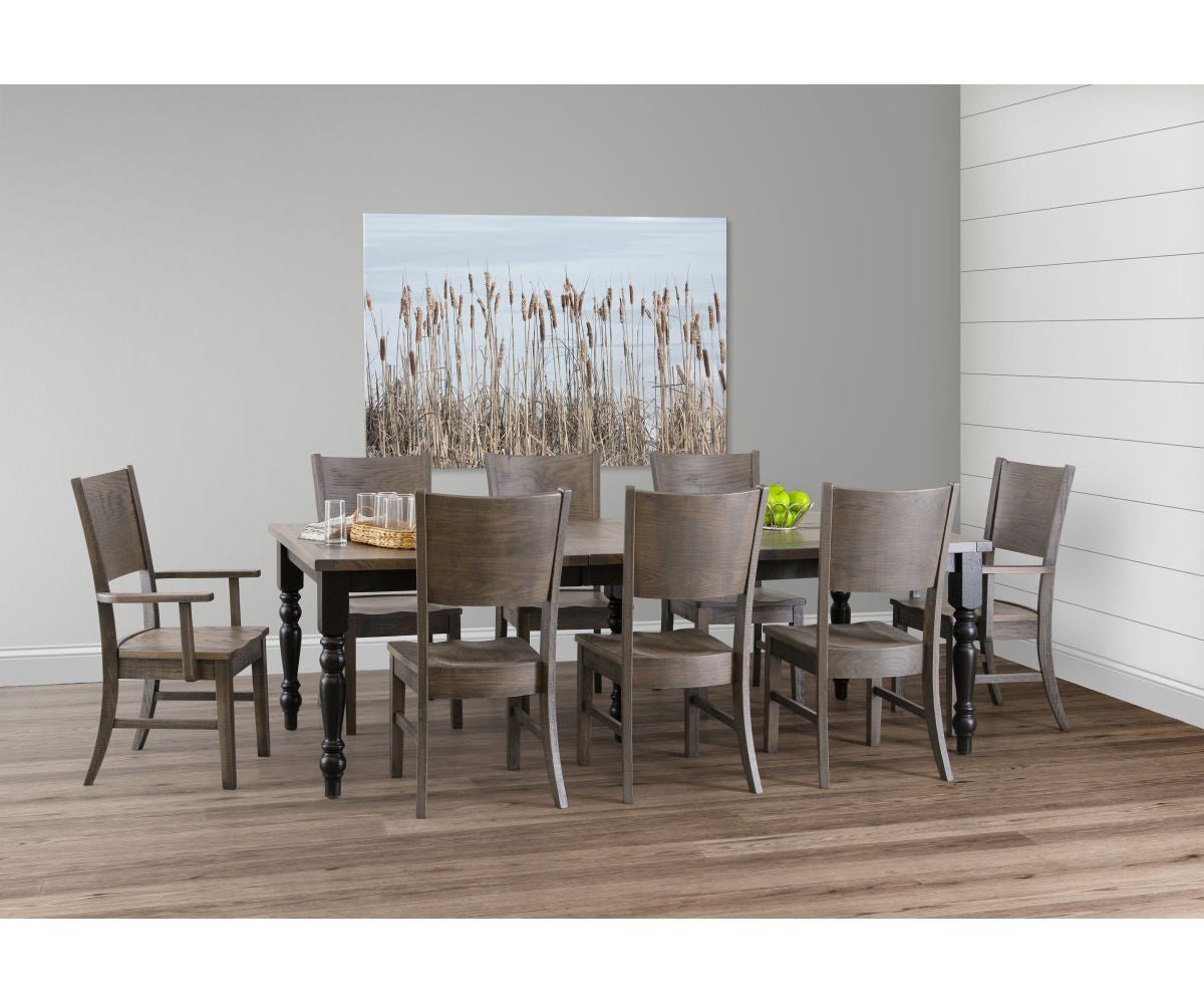 Gray weathered dining table with black turned legs, eight curved back chairs including an arm chair, in a dining room