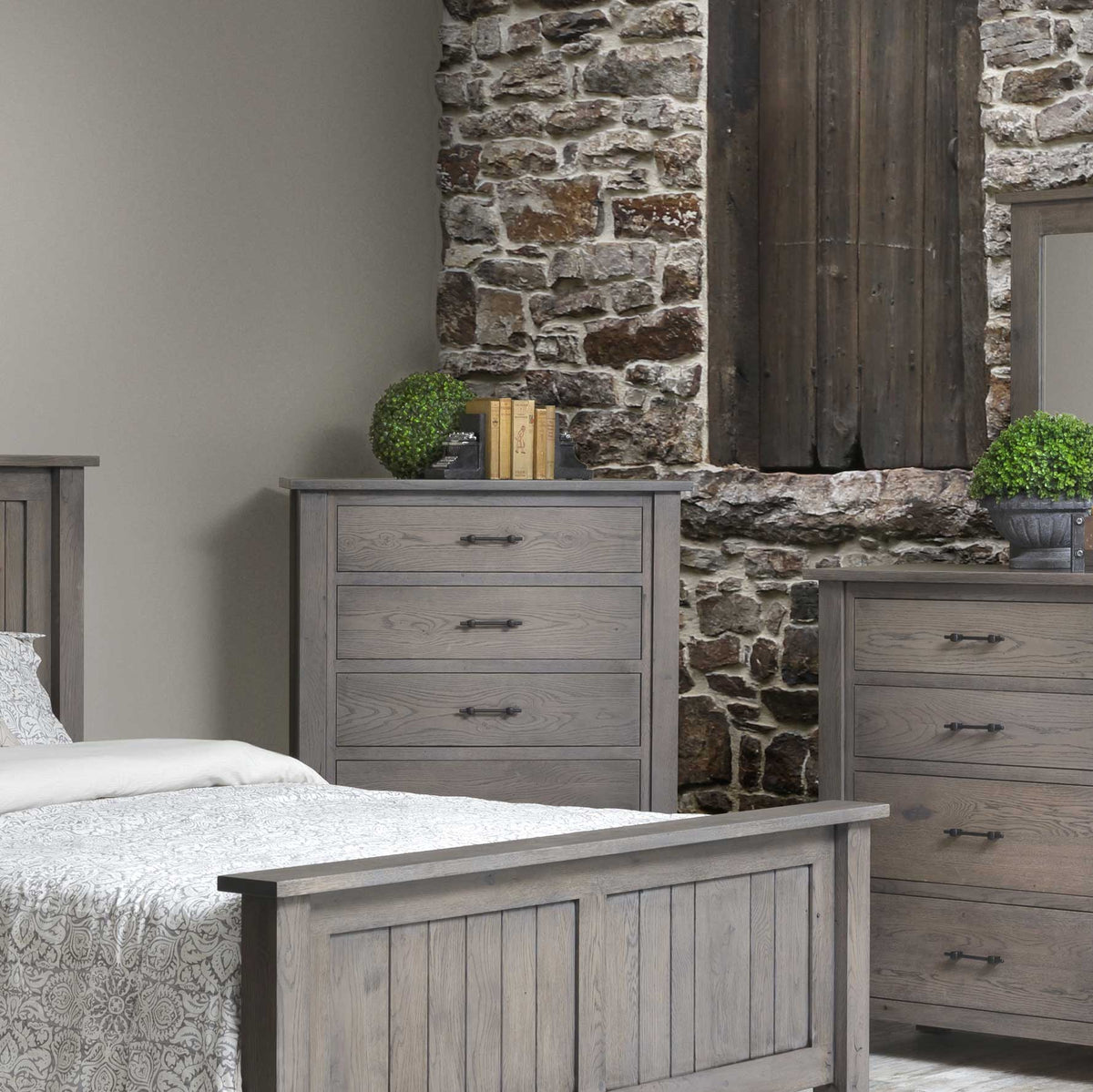 Gray plank chest of drawers and matching dresser in a rustic bedroom with a stone wall and barn wood shutters