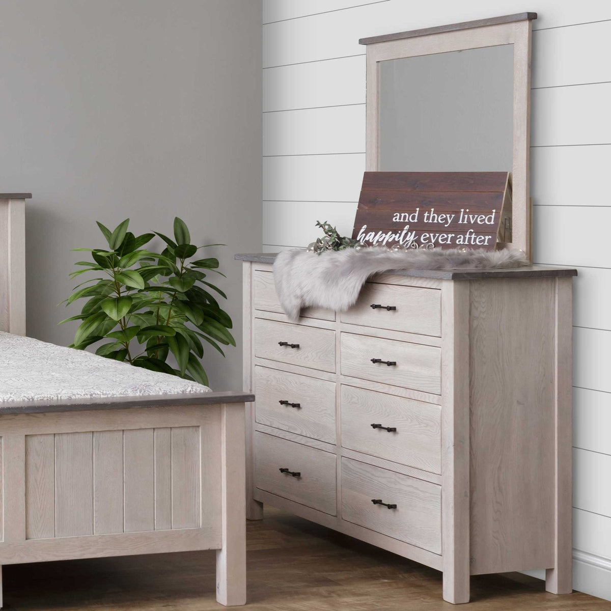 Whitewashed oak eight-drawer dresser with a contrasting gray top and matching mirror in a farmhouse bedroom with shiplap wall