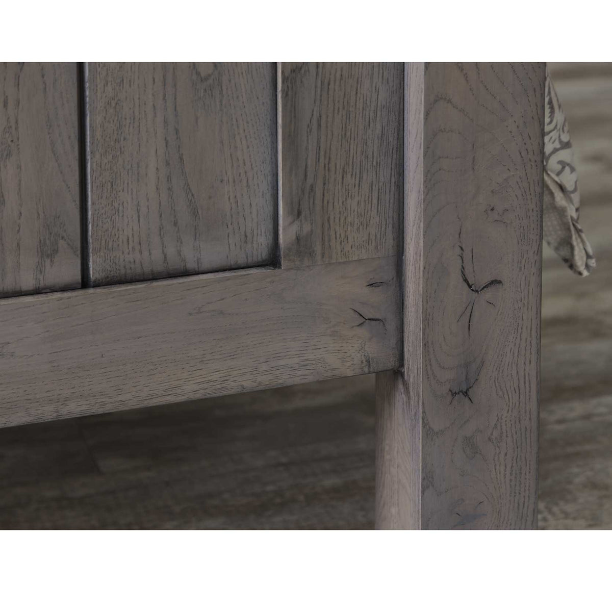 Close-up of the gray oak footboard rail, plank panel and knotted grain of the square leg post