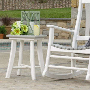 White poly patio side table with a gray top and splayed legs holding a lantern beside a white rocker
