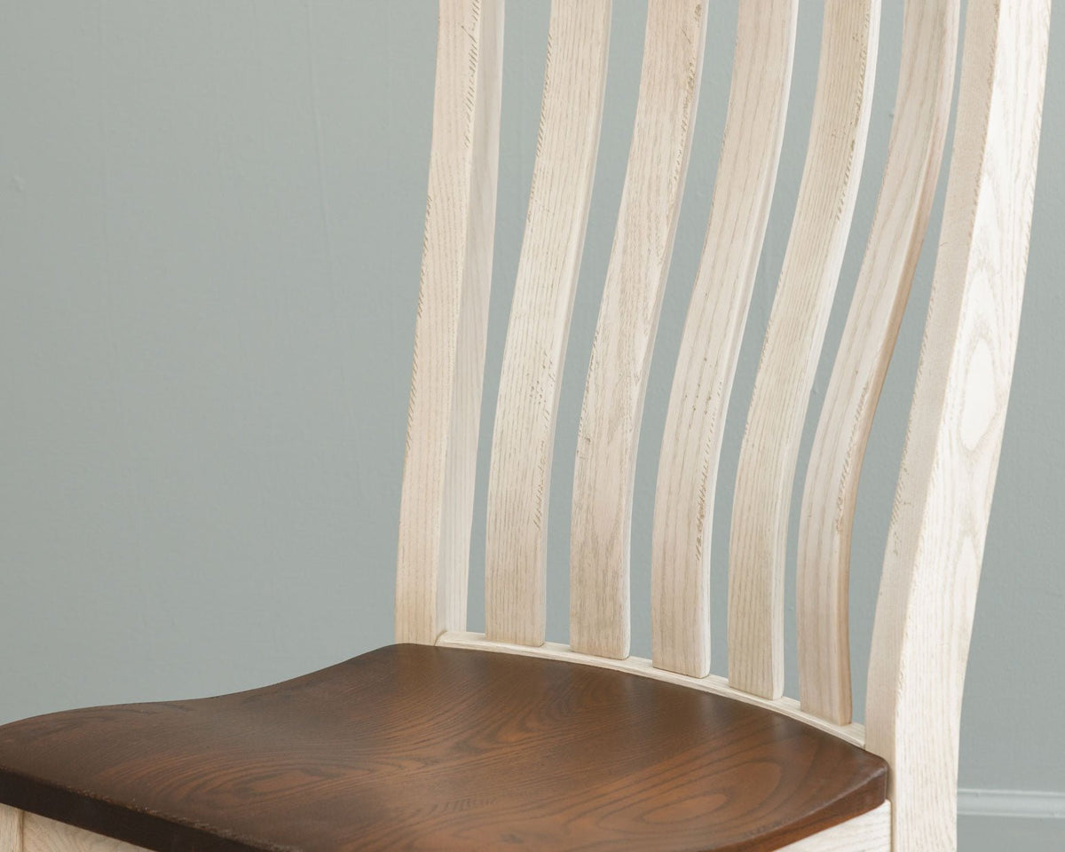 Close view of pale unfinished back slats curving above a dark brown stained dining chair seat