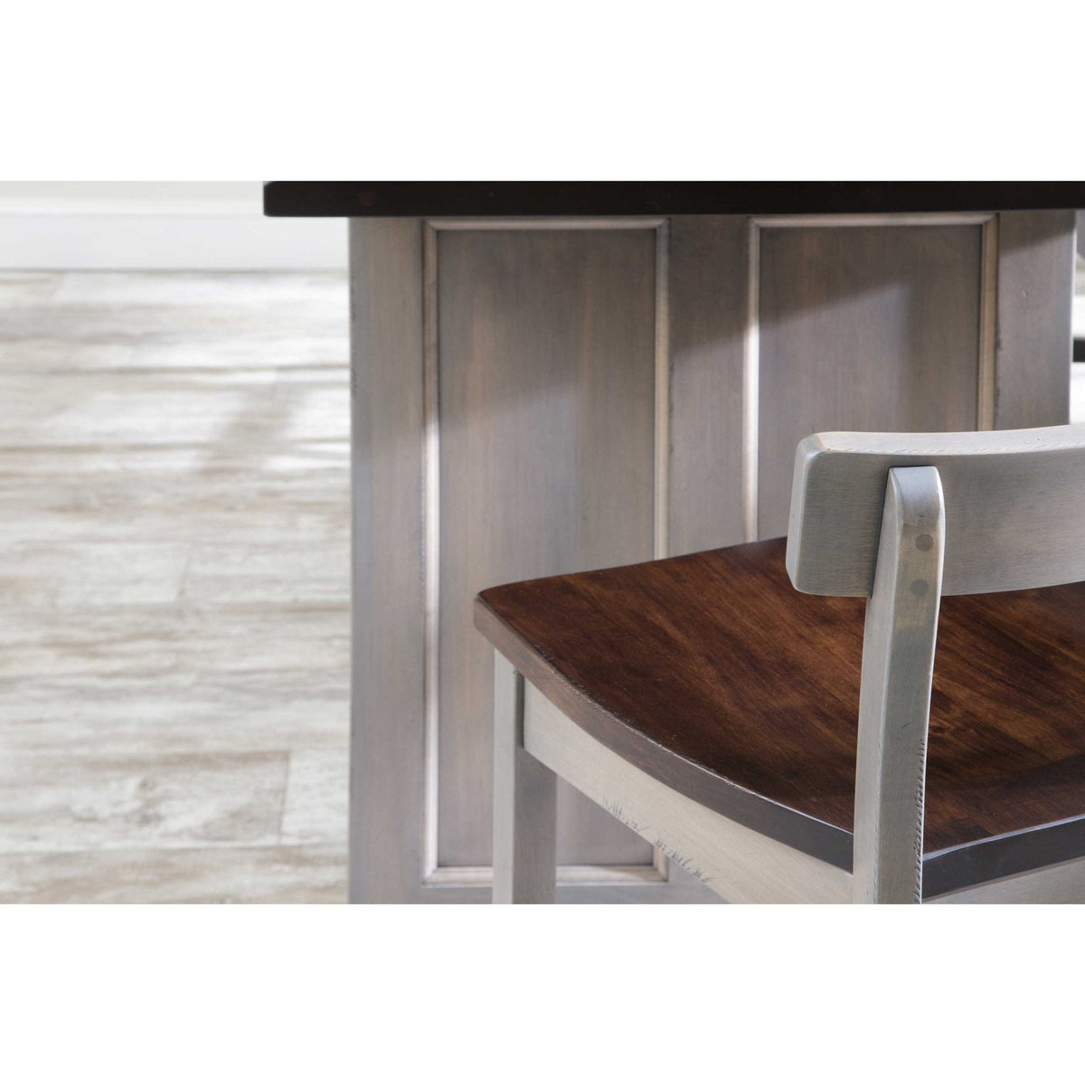 Detail of the kitchen island's raised side panel and saddle-seat counter stool with two-tone gray and brown finish