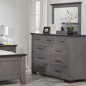 Gray nine drawer high dresser and mirror styled with orchids and a photo frame beside the bed