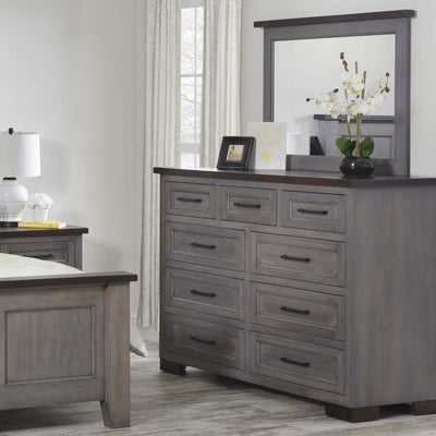 Gray nine drawer high dresser and mirror styled with orchids and a photo frame beside the bed