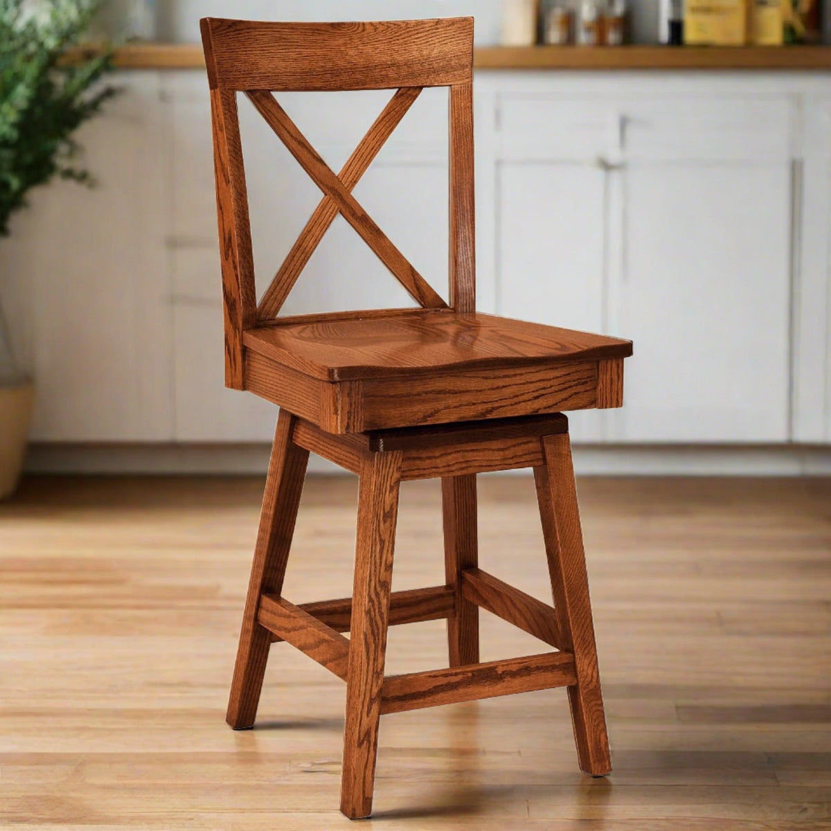 Oak X back swivel bar stool with a scooped seat and footrest rails standing in a bright kitchen