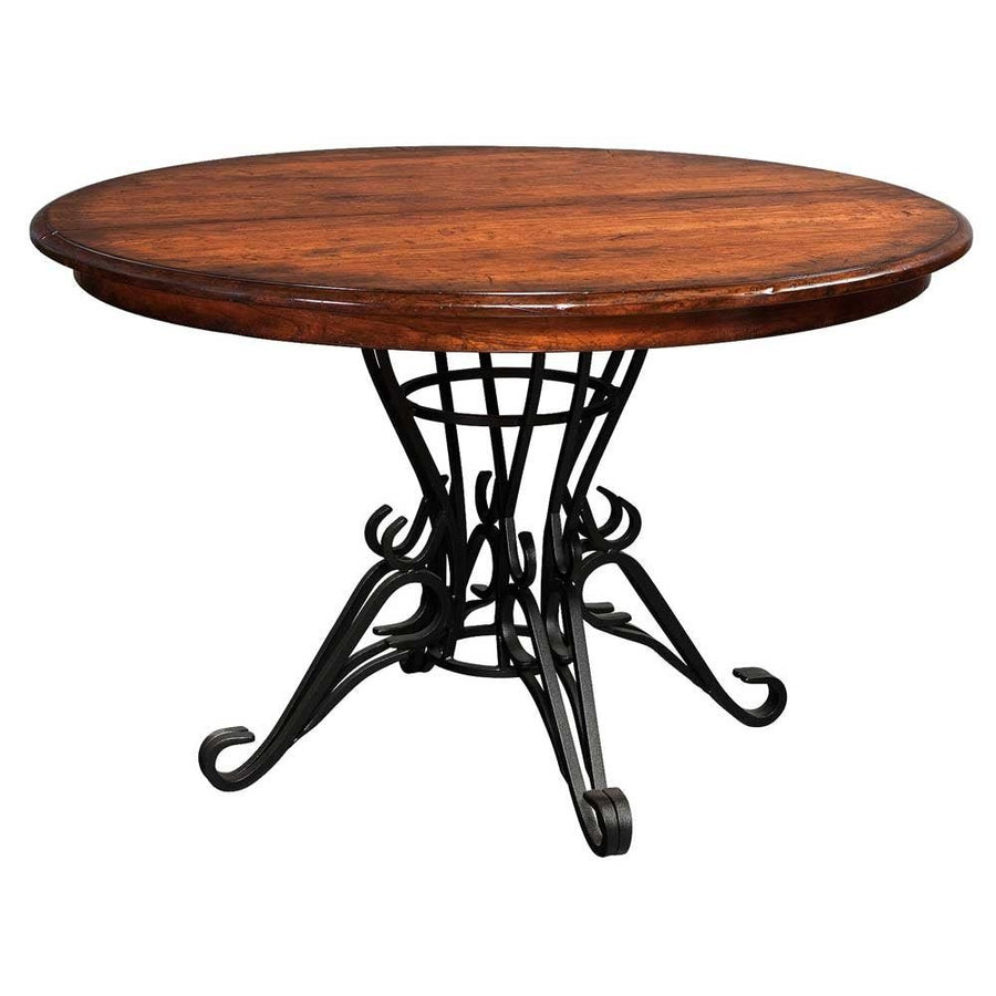 Round expandable dining table with a warm cherry top over a curling black wrought iron pedestal base