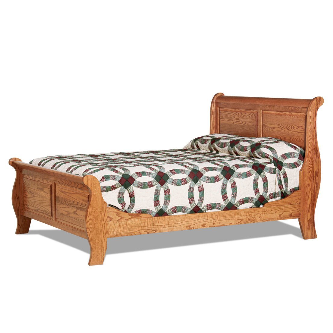 Oak sleigh bed with paneled scrolled headboard and footboard, wedding ring quilt, in a country bedroom with braided rug