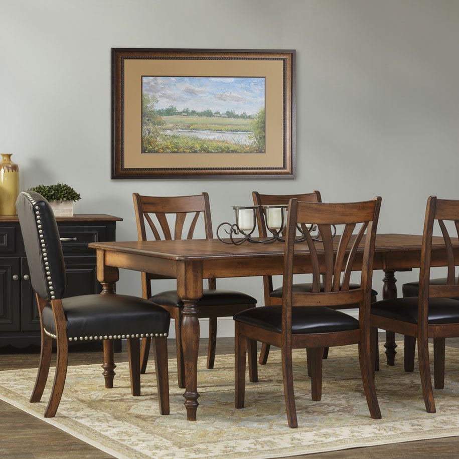 Formal dining room scene with a solid wood rectangular table in a warm brown finish, six chairs with black leather seats and framed artwork
