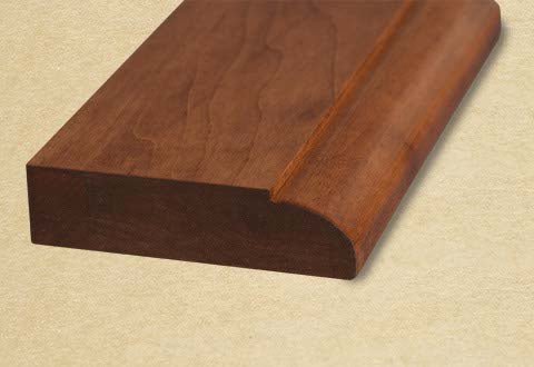Close-up of the solid cherry table edge profile showing the rounded bullnose routing and smooth stained finish