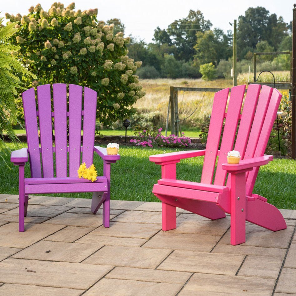 Purple and pink kids poly Adirondack fanback chairs with cupcakes on the wide arms on a paver patio