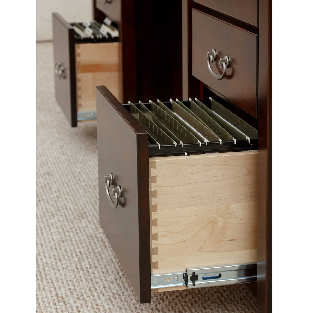 Close-up of an open dovetailed file drawer with hanging file rails, full extension glides and ring pulls